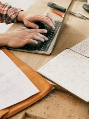 A woodworker uses a laptop to design furniture in a workshop setting, highlighting the blend of technology and craftsmanship.